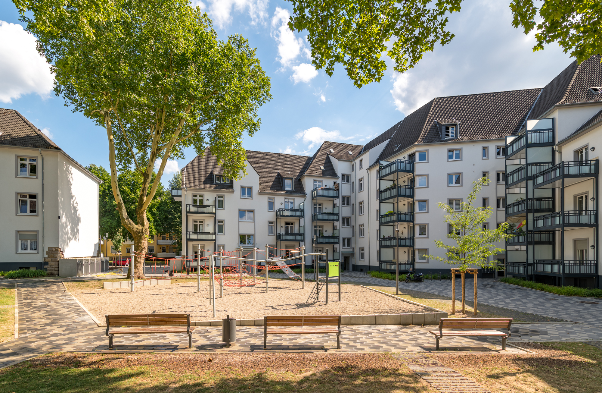 Wohnhäuser mit Balkonen und einem Spielplatz davor.