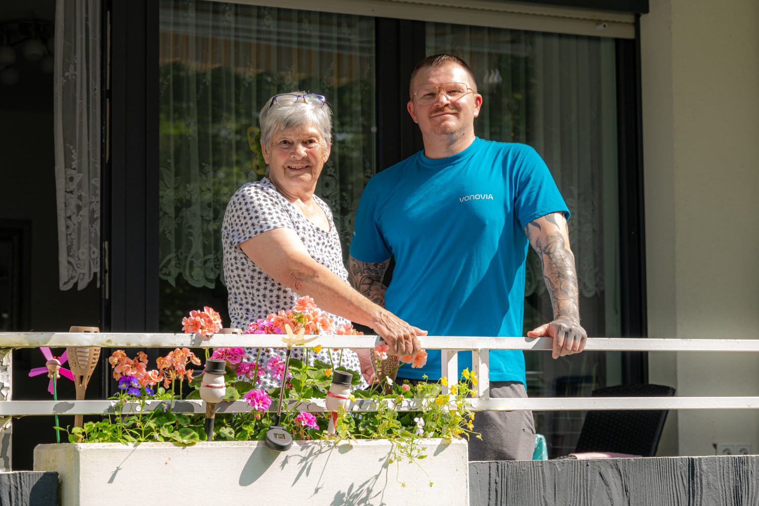 Eine Mieterin und ein Mitarbeiter der Vonovia stehen auf einem Balkon.